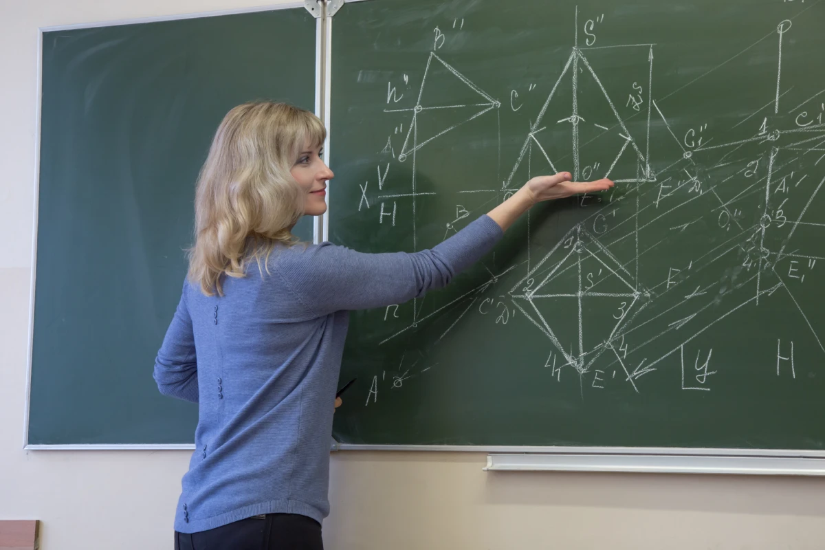 woman-teaching-while-standing-by-blackboard-classroom-v3